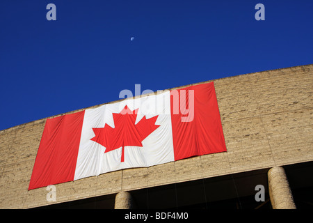 Moon in the blue sky above the Canadian flag. Stock Photo