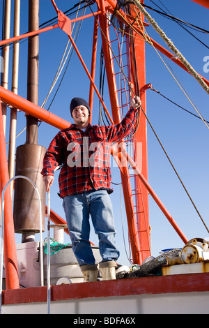 Young fisherman in plaid shirt standing on fishing boat Stock Photo