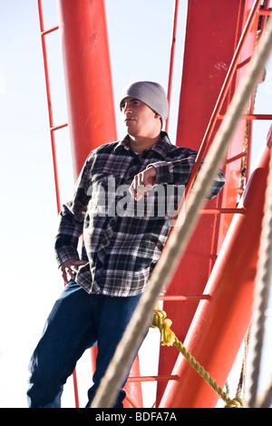 Young fisherman in plaid shirt standing on fishing boat Stock Photo