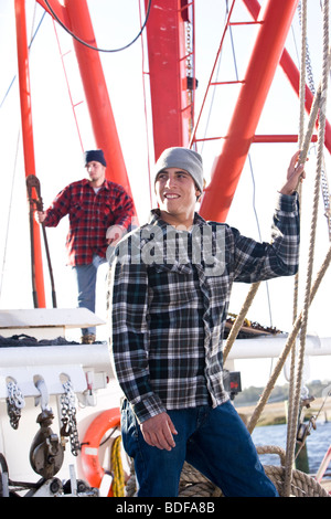 Young fishermen in plaid shirts standing on fishing boat Stock Photo