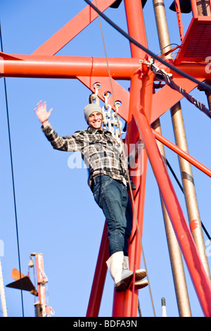 Young fisherman in plaid shirt climbing on fishing boat and waving Stock Photo