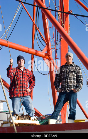 Young fishermen in plaid shirts standing on fishing boat Stock Photo