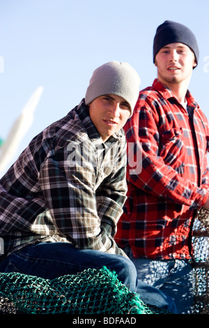 Young fishermen in plaid shirts on fishing boat Stock Photo