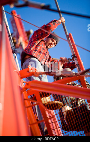 Low angle view of young fishermen in plaid shirt fixing pipe on fishing boat Stock Photo