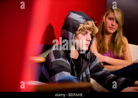 Young unhappy teenage couple sitting on sofa indoors Stock Photo