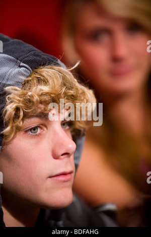 Close-up of young teenage boy, teenage girl in background Stock Photo