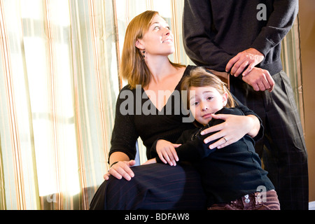 Family of three posing for portrait in front of window Stock Photo