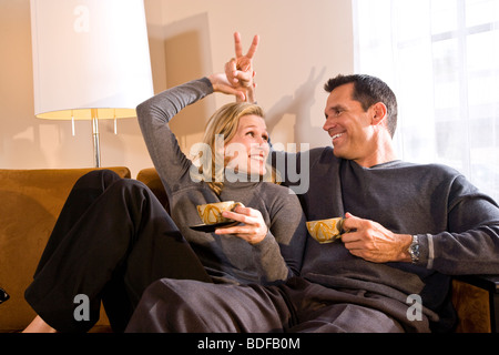 Mid-adult couple relaxing on sofa together drinking tea Stock Photo
