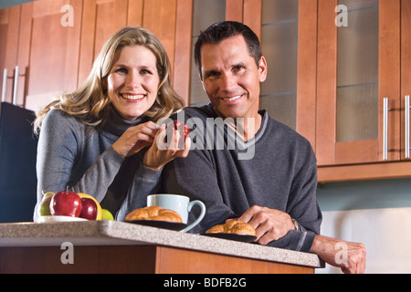Mid-adult couple standing in kitchen having breakfast Stock Photo