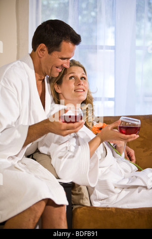 Romantic mid-adult couple relaxing on sofa together drinking red wine Stock Photo