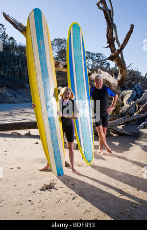 Middle-aged couple in wetsuits on beach with surfboards Stock Photo