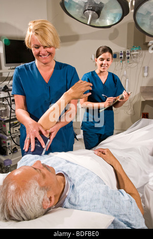 Nurses taking blood pressure of patient in hospital room Stock Photo