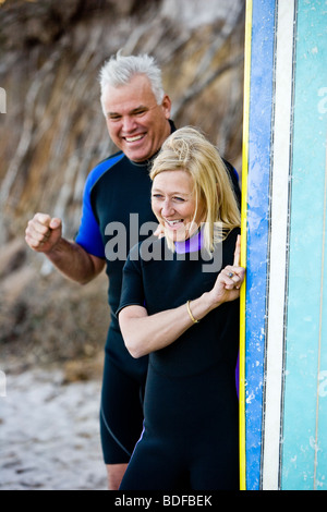 Middle-aged surfer couple on beach with surfboard Stock Photo