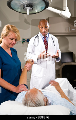 Nurses taking blood pressure of patient in hospital room Stock Photo