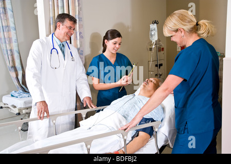 Doctor and nurses in hospital recovery room with patient Stock Photo