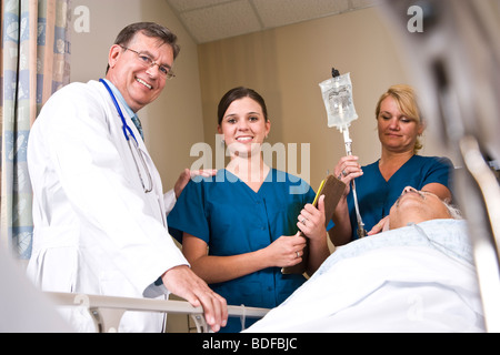 Doctor and nurses in hospital recovery room with patient Stock Photo