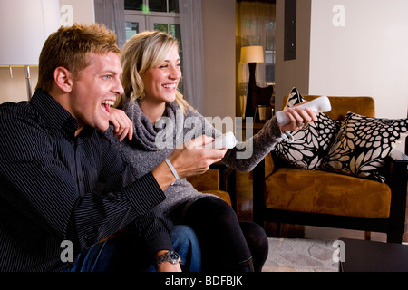 Young couple playing video games in living room Stock Photo