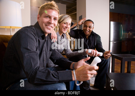 Multi-ethnic group of adult friends playing video games in living room Stock Photo