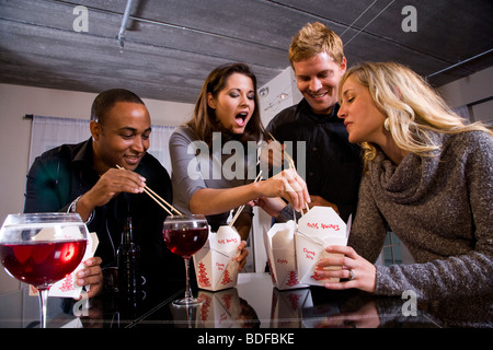 Multi-ethnic couples eating Chinese take-out in modern loft Stock Photo