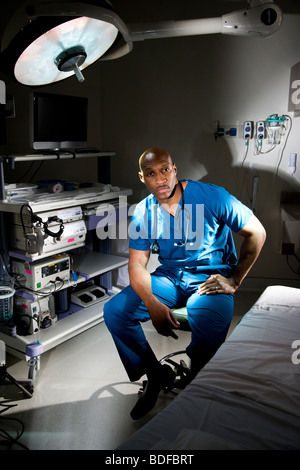 African-American doctor in scrubs sitting in hospital room Stock Photo