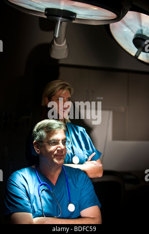 Portrait of doctors in scrubs standing in hospital room with surgical lights Stock Photo