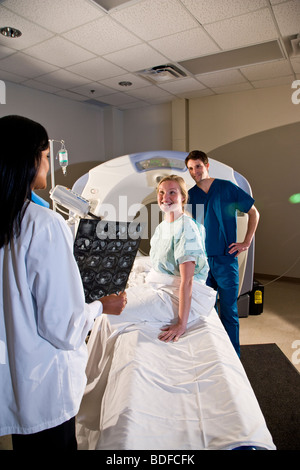 Two healthcare workers looking over CAT scan results with patient Stock Photo