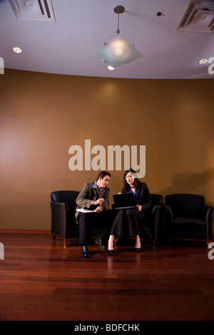Two business people in lounge area  working together on laptop Stock Photo