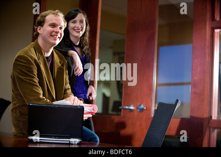 Casual businesspeople relaxing and laughing in office Stock Photo