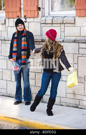 Young woman playfully pulling boyfriend on sidewalk Stock Photo
