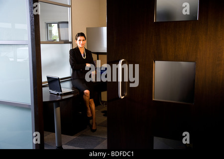 Hispanic businesswoman sitting in office Stock Photo