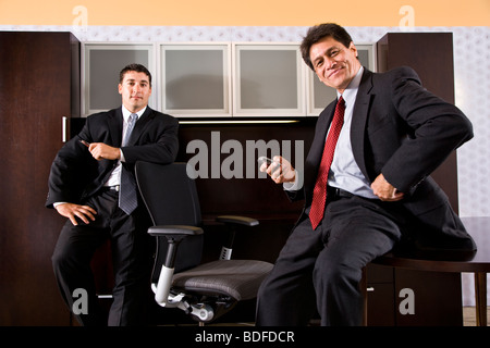 Portrait of two Hispanic businessmen sitting in office, looking at camera Stock Photo