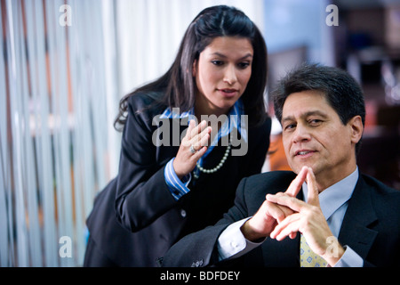 Hispanic businessman thinking, assistant giving advice Stock Photo
