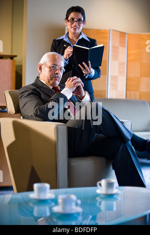 Hispanic businessman with assistant taking notes behind Stock Photo
