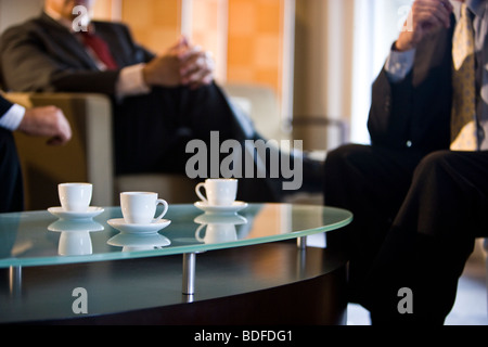 Coffee cups on table, business executives meeting in background Stock Photo
