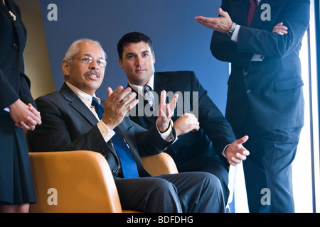 Hispanic senior executive surrounded by office staff Stock Photo