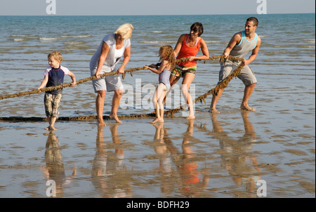 Family holidaying on the beach and enjoying a game of tug of war southern England UK