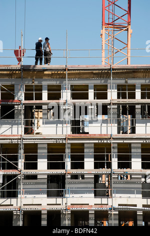 two construction workers on top of office building under construction Stock Photo