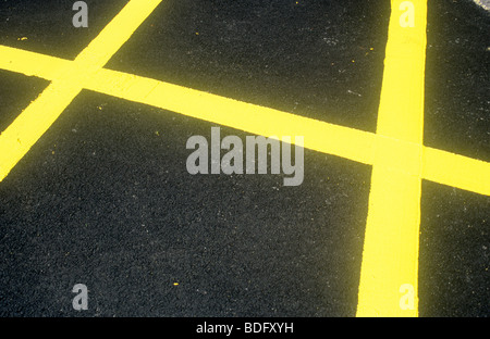 Fresh yellow lines painted on recent tarmac surface as part of a No Parking or No Waiting grid Stock Photo