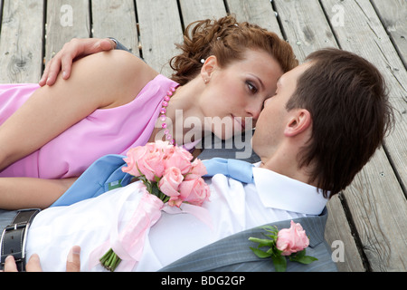 Newlyweds laying down on the wood floor  and kissing. Stock Photo