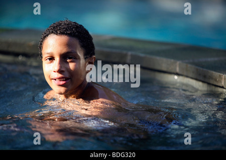 11 year old boy in a backyard swimming pool Stock Photo