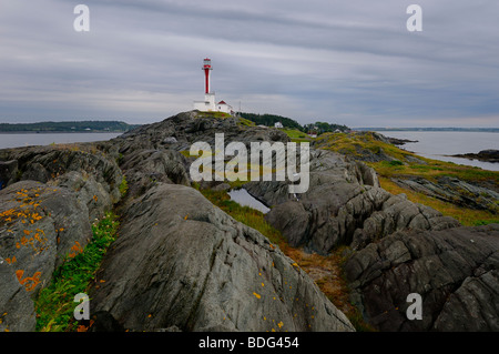 Cape Forchu lighthouse peninsula on the Atlantic Ocean with wet rocks and grass Yarmouth Harbour Nova Scotia Stock Photo