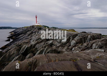 Cape Forchu peninsula and lighthouse on the Atlantic Ocean with wet rocks at Yarmouth Harbour Nova Scotia Stock Photo