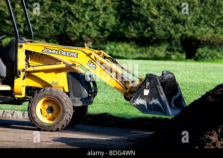Green John Deere tractor with bucket on front and red trailer parked on  path Stock Photo - Alamy