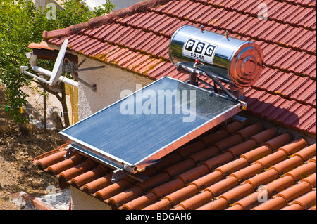 Domestic solar panel water heater on tiled roof of house at Assos on the Greek Mediterranean island of Kefalonia Greece GR Stock Photo