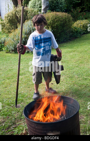 Young boy aged seven burning rubbish in garden Stock Photo