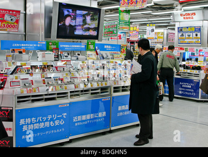 Man reviewing digital cameras in Japanese electronics shop, Tokyo Japan Stock Photo