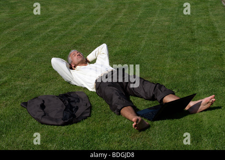 Handsome businessman lying down on grass Stock Photo