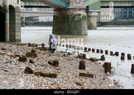 A man searches the thames foreshore with a metal detector Stock Photo