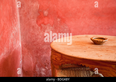 Small table, ash tray and stool in a Moroccan café with a bright red wall Stock Photo