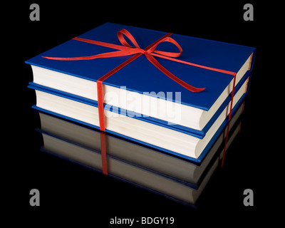 Two blue books with red silk ribbon, isolated on black background. Stock Photo
